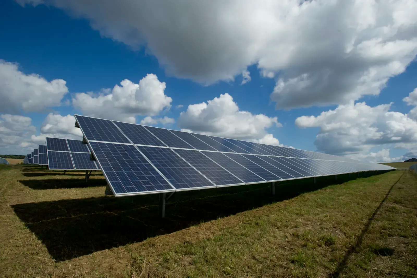Rows of photovoltaic solar panels on a green field under a cloudy sky in Indiana